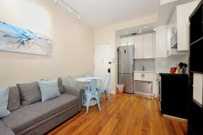 a living room with a couch and a table and a kitchen at Comfy 1 Bed 1 Bath Apartment in NYC in New York