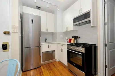 a kitchen with white cabinets and a stainless steel refrigerator at Comfy 1 Bed 1 Bath Apartment in NYC in New York