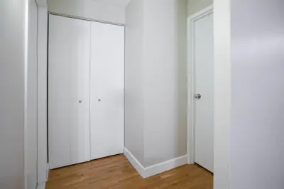 a room with white closet doors and wood floors at Fully Furnished 2BR 2Bath Unit in NYC in New York