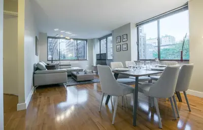 a dining room with a table and chairs and a couch at Fully Furnished 2BR 2Bath Unit in NYC in New York