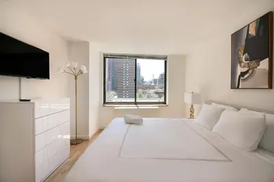 a white bedroom with a large white bed and a window at Stunning Apartment for 4 2 Bedrooms 2 Bath in New York