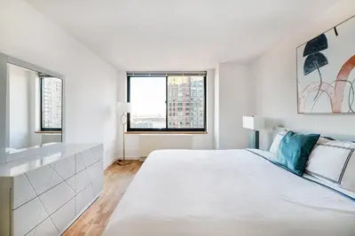 a white bedroom with a large bed and two windows at Luxury 2 Bed 2 Bath Unit in Prime Location of NYC in New York