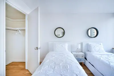 a white bedroom with two beds and a mirror at Luxury 2 Bed 2 Bath Unit in Prime Location of NYC in New York