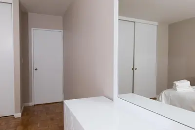 a white room with a mirror and a bed at 2 Bed Apt Ideally located in UES of Manhattan in New York