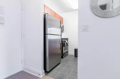a stainless steel refrigerator in a kitchen with a tile floor at Fully Furnished 1BR in Murray Hills in New York