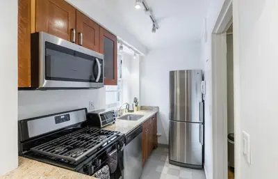 a kitchen with a stove and a stainless steel refrigerator at Lovely Studio New York Apartment in New York