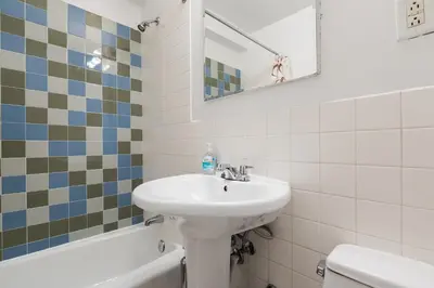 a bathroom with a sink and a mirror and a tub at Lovely Studio New York Apartment in New York