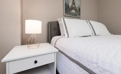 a bedroom with a white bed with a lamp on a night stand at Lovely Studio New York Apartment in New York