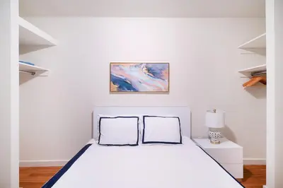 a white bedroom with a bed and a painting on the wall at Contemporary 1 Bedroom Apartment in NYC in New York
