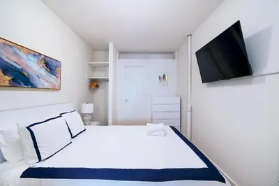 a bedroom with a white bed and a flat screen tv at Contemporary 1 Bedroom Apartment in NYC in New York