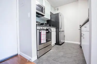 a kitchen with stainless steel appliances and white walls at Fully Furnished Studio Apartment in New York