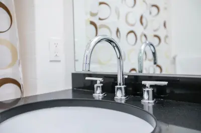 a bathroom counter with a sink and two faucets at Fully Furnished Studio Apartment in New York