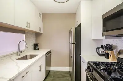 a kitchen with white cabinets and a stainless steel refrigerator at Gorgeous Studio Apartment in New York
