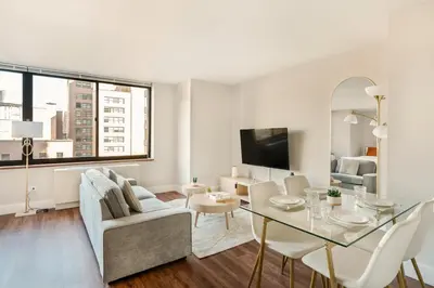 a white living room with a table and a couch at Gorgeous Studio Apartment in New York