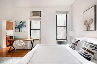 a white bedroom with a bed and a desk at Bright and Comfy Studio in NYC in New York