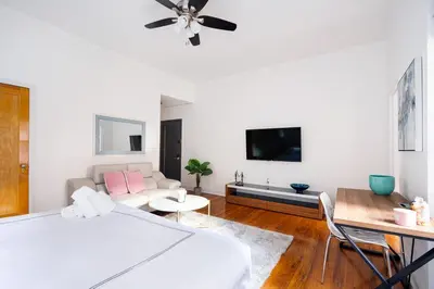 a white bedroom with a bed and a couch at Bright and Comfy Studio in NYC in New York