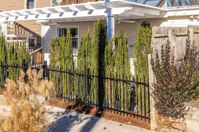 a fence in front of a house with trees at Cottage At Yale in New Haven
