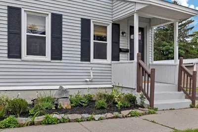 a house with a porch with a fence and flowers at Charming Family Saratoga Home Walk to Track & Downtown in Saratoga Springs
