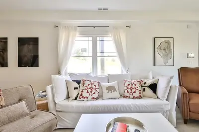 a living room with a white couch with pillows at Trailside Escape 2BR Views Fireplace & Balcony in Hunter