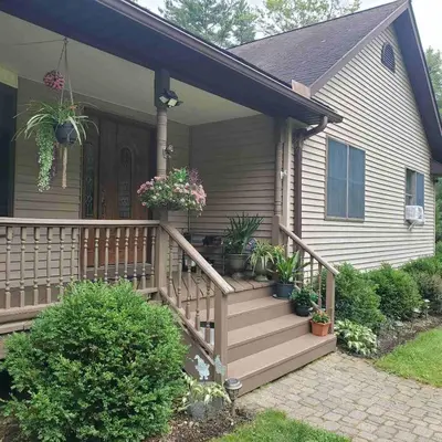 a house with a wooden porch with potted plants at Spacious House with a Pool in Glen Spey