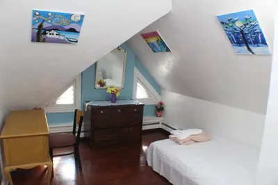 a attic room with two beds and a dresser and a mirror at Whitney Wonder 2nd and 3rd floor in Hartford