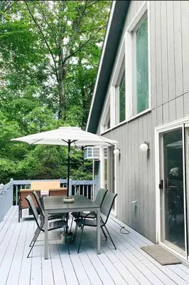 a table and chairs with an umbrella on a deck at Cozy Retreat in Scenic Poconos in Tobyhanna