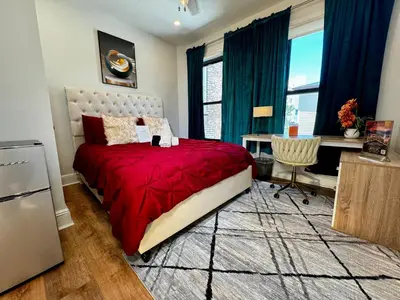 a bedroom with a bed with a red comforter and a desk at BP STAYS - Hotel-Style, No Host, Professionally Managed ID297 in Jersey City