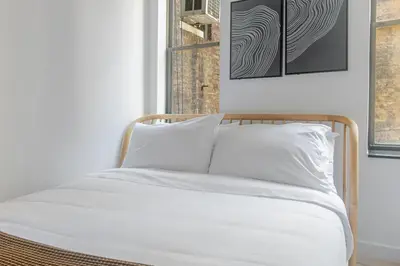 a bed with white sheets and pillows in a room at Blueground Chinatown washer nr City Hall NYC-1871 in New York