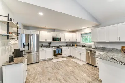 a large kitchen with white cabinets and stainless steel appliances at Fish and Swim Home with Catskill Creek Views! in East Durham