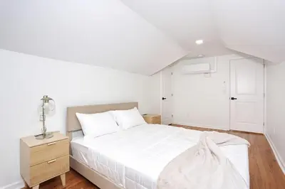 a white bedroom with a bed and a night stand at NEW Modern NYC Escape near MetLife AmDream MALL EWR in Bergenfield