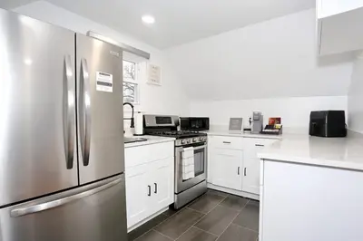 a kitchen with stainless steel appliances and white cabinets at NEW Modern NYC Escape near MetLife AmDream MALL EWR in Bergenfield