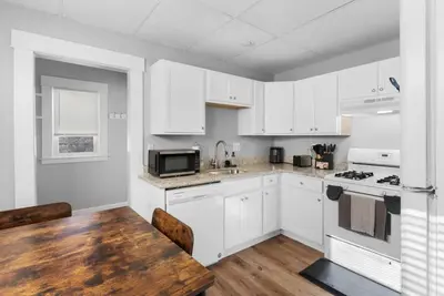 a kitchen with white cabinets and a wooden table at SCSU Two Bedroom Suite in New Haven