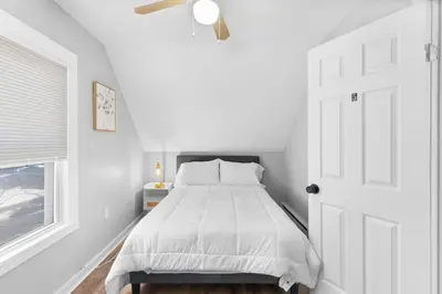 a white bedroom with a bed and a window at SCSU Two Bedroom Suite in New Haven