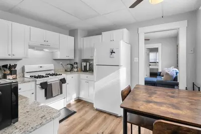 a kitchen with white cabinets and a table and a refrigerator at SCSU Two Bedroom Suite in New Haven