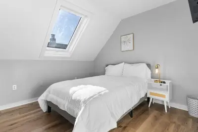 a white bedroom with a bed and a window at SCSU Two Bedroom Suite in New Haven
