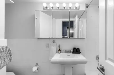 a white bathroom with a sink and a mirror at Bold Manhattan Base in Prime Nolita in New York