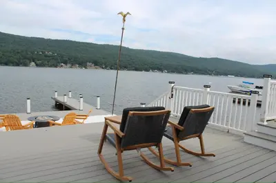 two chairs sitting on a deck next to the water at Lakefront Haven on Greenwood Lake in West Milford
