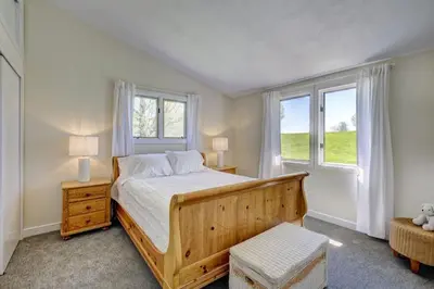 a bedroom with a wooden bed and two windows at Cottage in the woods in Salisbury