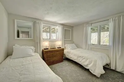 two beds in a bedroom with two windows at Cottage in the woods in Salisbury