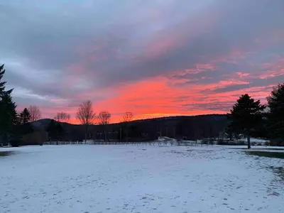 a snow covered field with a sunset in the background at Cottage in the woods in Salisbury