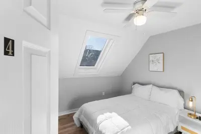 a white bedroom with a bed and a window at Owl's Nest - 5BR apartment in New Haven