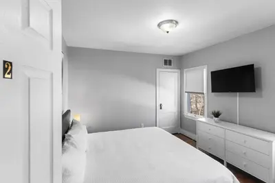 a white bedroom with a bed and a flat screen tv at Owl's Nest - 5BR apartment in New Haven