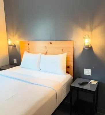 a bed with two pillows and a night stand next to it at Bklyn House Hotel New York Brooklyn in Brooklyn