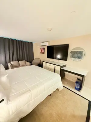 a bedroom with a bed and a desk and a television at Nova Hotel Bronx in Melrose