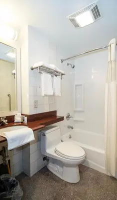 a white bathroom with a toilet and a sink at Nova Hotel Bronx in Melrose