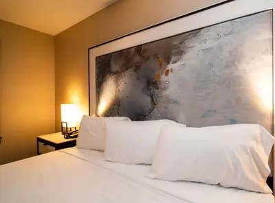 a large painting above a bed with white pillows at Nova Hotel Bronx in Melrose