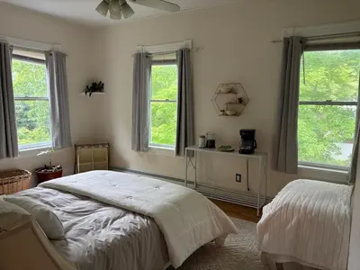 a bedroom with a bed and two windows at Charming Three Bedroom Retreat House in Saugerties