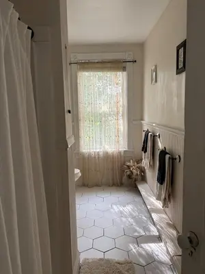 a bathroom with a window and a white tile floor at Charming Three Bedroom Retreat House in Saugerties