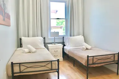 two beds in a small room with a window at 15 Minutes From Manhattan 2-Bedroom Apartment in LIC Astoria Queens