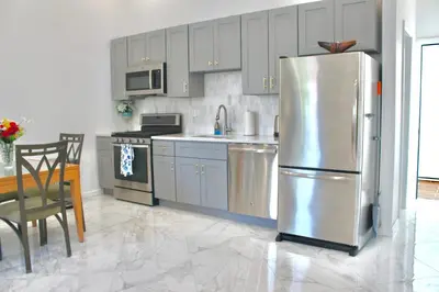 a kitchen with a stainless steel refrigerator and a table at 15 Minutes From Manhattan 2-Bedroom Apartment in LIC Astoria Queens